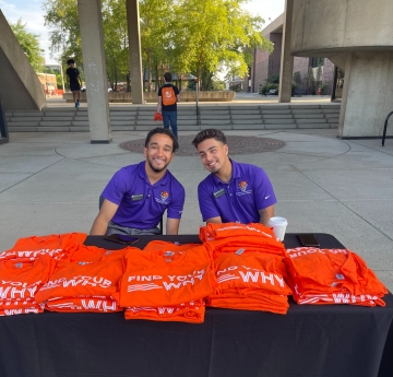 BEAT Team Members sitting at a table passing out shirts